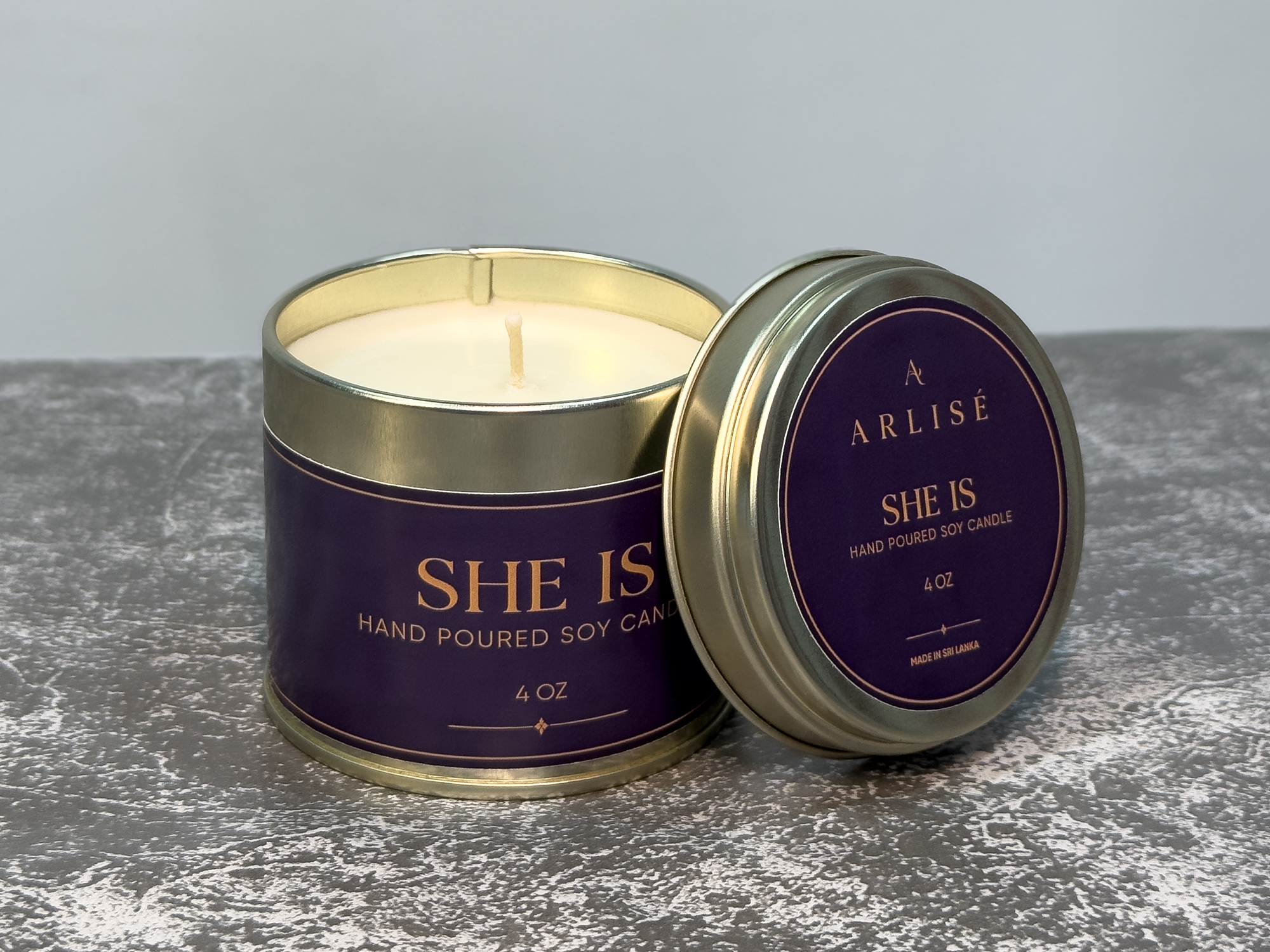 SHE IS Ceylon cinnamon leaf soy candle in its tin, unlit, in warm daylight